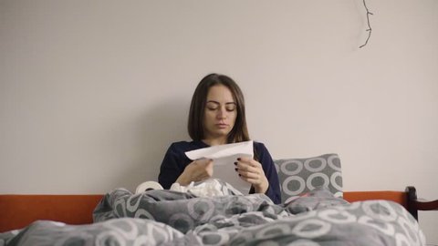 Young woman blowing nose in the bed