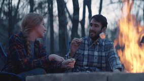 Young man and woman sit beside a fire and make s’mores  - Powered by Shutterstock - Get 15% off with code: PIKWIZARD15