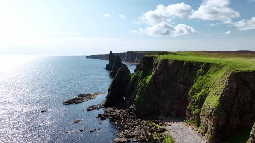 Circular drone shot of the Duncansby sea stacks emerging from behind the cliff. Duncansby Stack, Scotland.