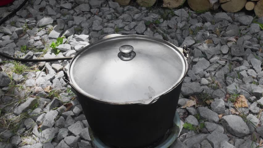 The soup is cooked in a large cauldron over an open fire during the day.