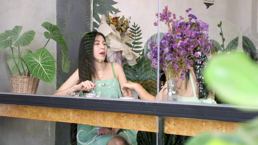 Two Asian females spend free time together in cafe coffee shop, freelance woman workers or colleagues consult of share job ideas in eatery restaurant, single woman lifestyle, candid shot from window