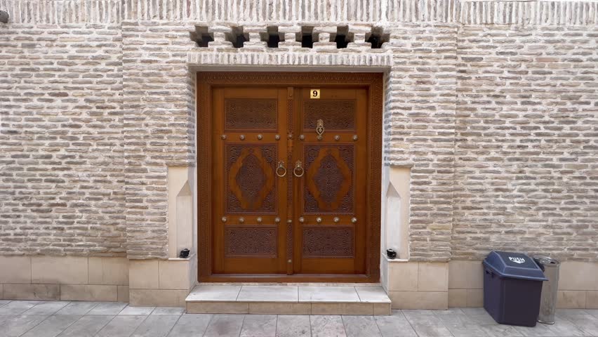 Step into History: 4K Static View of a Young Man Emerging from a Traditional Wooden Door in Historic Bukhara Old Town, Uzbekistan