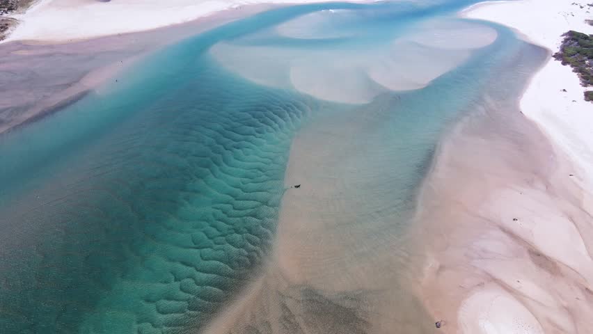 Lagoon mouth breaches into the ocean with sand dunes and sediment creating beautiful patterns Royalty-Free Stock Footage #3417216023