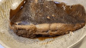 A video of pouring broth onto flounder fillets on a plate. A flounder with an egg inside.