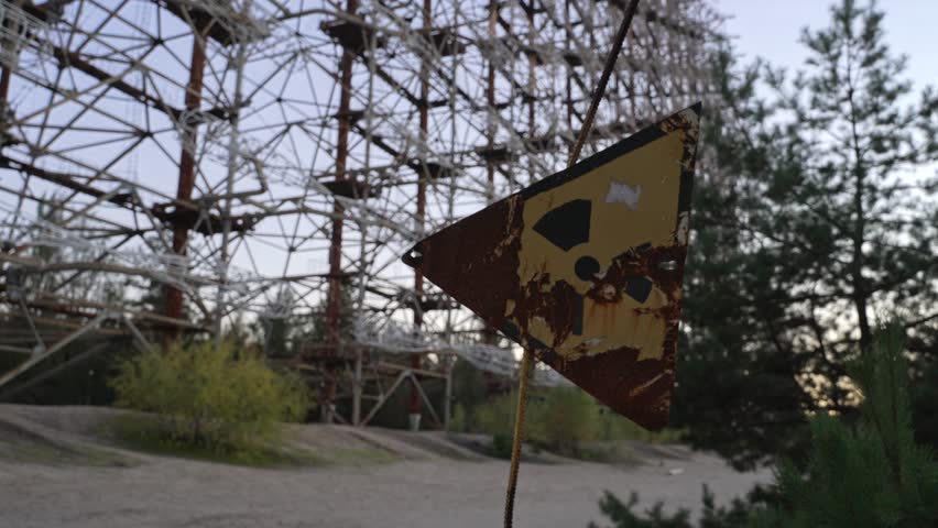 Zoom out from abandoned radiation sign with Duga horizon radar systems on background in Chernobyl, Ukraine 