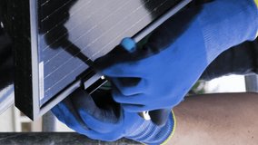 Vertical Close-Up View of a Technician's Hands Installing a Solar Panel