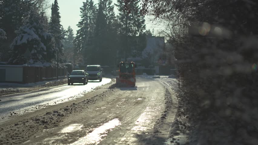 Snow removal in city with special vehicles. Winterdienst in Deutschland. Snowblower clears pavement and bicycle track in Munich, Germany after snowfall in sunny weather. Tractor cleans snowy walkway.  Royalty-Free Stock Footage #3417356643