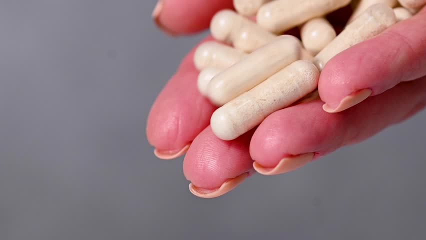 Female hands holding a heap of white capsules, Collagen, vitamins, pain killers, food supplements pills.