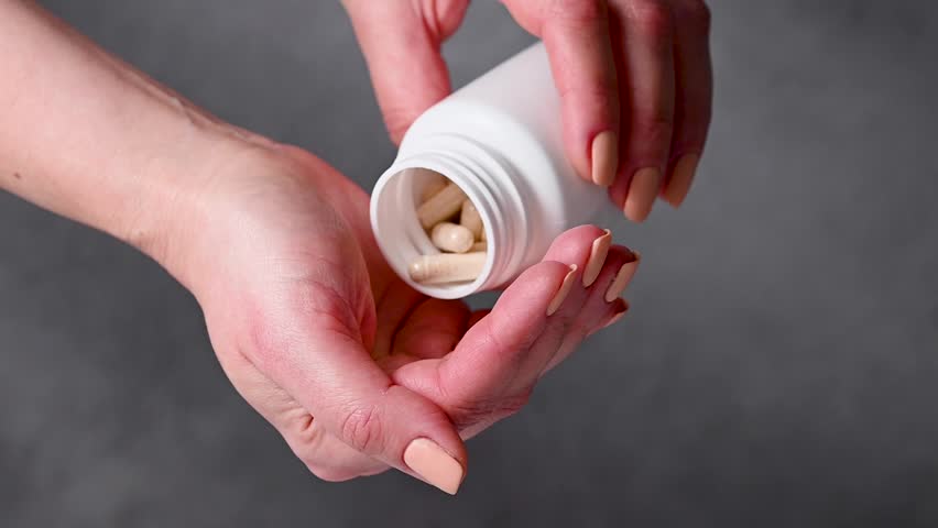 Female hands holding a heap of white capsules, Collagen, vitamins, pain killers, food supplements pills.