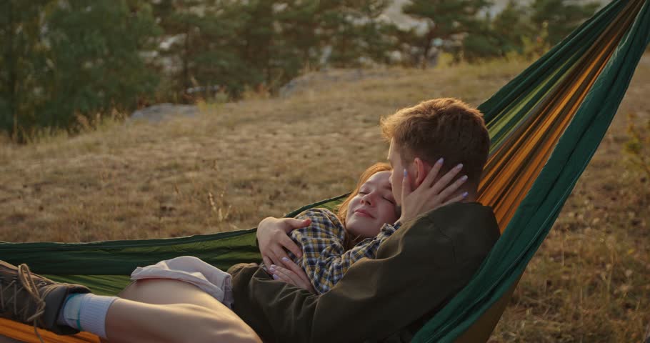 Couple in love hugging in a hammock at sunset in a pine forest. Royalty-Free Stock Footage #3417478699
