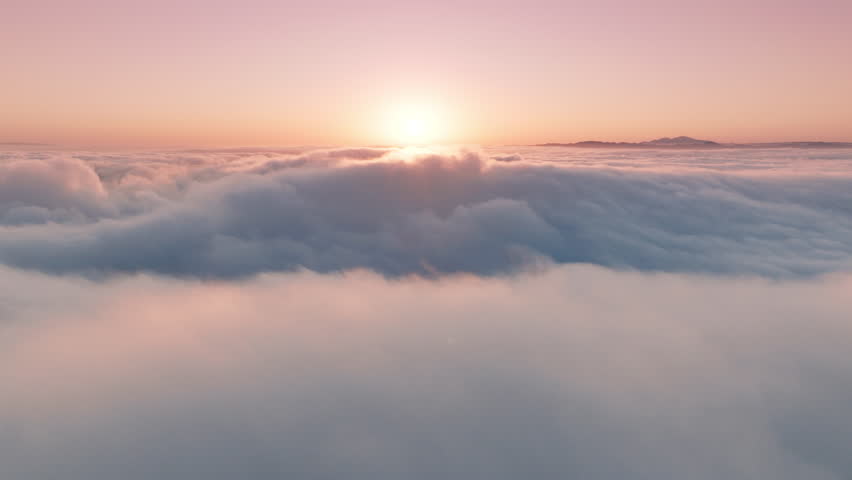 Epic aerial view over paradise cloudscape at sunrise or sunset. Wonderful inspirational sky with gentle pastel pink, peach and light blue clouds swirling fast below. Time lapse above beautiful clouds