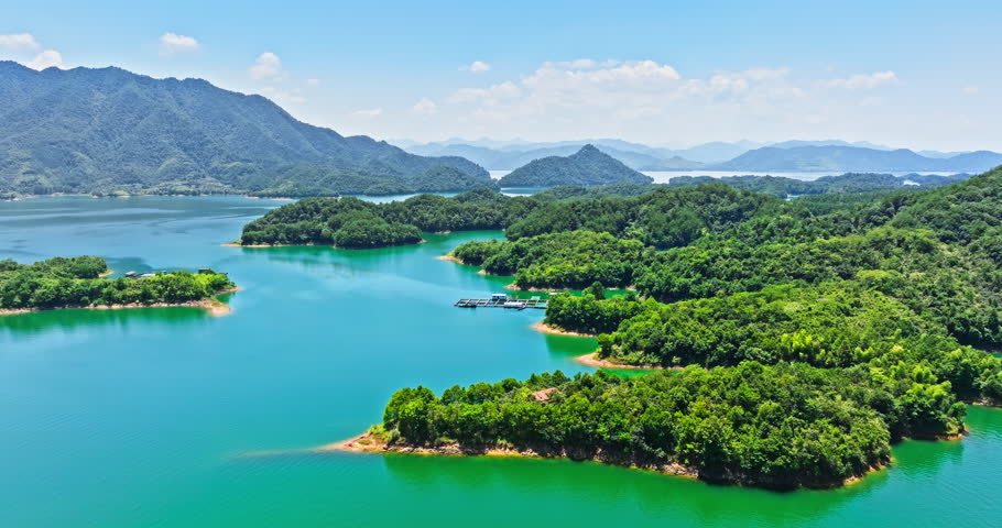 Aerial video of clear lake water and green island with mountain natural landscape in Hangzhou. Drone moves forward and rises to shoot.