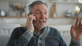 Positive senior man calls phone at home. Portrait old gray haired male talking on smartphone sitting on couch, smiling laughing enjoying conversation with friend, relative. Happy sociable person. - Powered by Shutterstock - Get 15% off with code: PIKWIZARD15