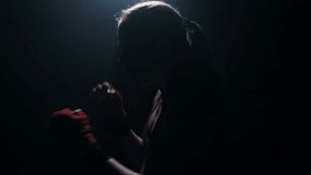 Woman boxer boxing with shadows in a semi-dark room practicing punches shadow boxing, slow motion. Video for motivation, goal achievement, success