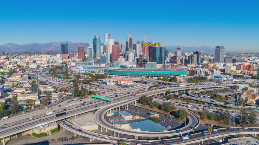 Urban aerial timelapse of downtown Los Angeles convention center, freeways, highways, interstates with heavy traffic on a sunny blue sky day.