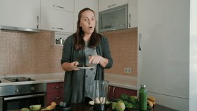 Young woman blogger woman cooking green vegetable smoothie for Video-sharing website at kitchen

