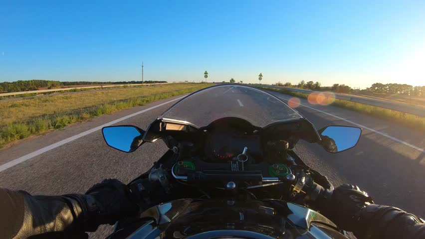 Point of view of a motorcycle rider rides in speed highway. The viewpoint of motorcyclist driving motorbike at empty country route. Guy racing his motor bike during summer journey. POV