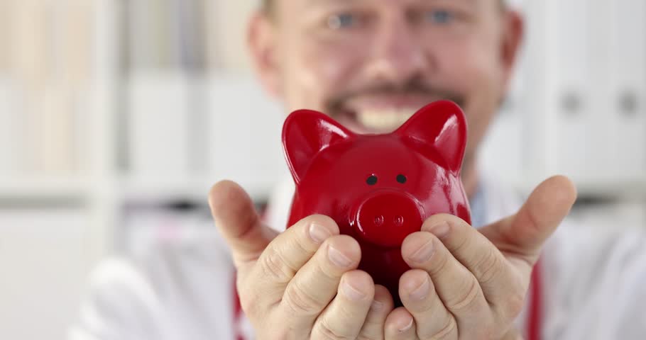 Smiling doctor is holding piggy bank. Medical insurance concept Royalty-Free Stock Footage #3417864047
