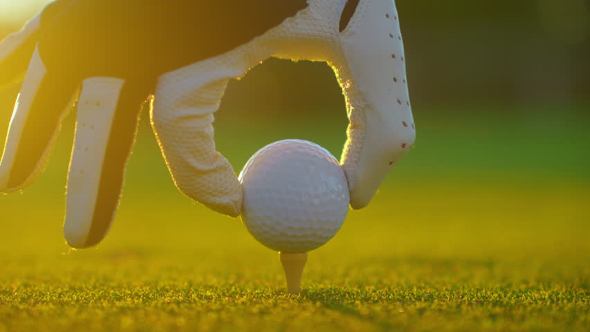 Golfer placing golf ball on the tee at golf course. Close up. People, sport, leisure activity, recreation and lifestyle