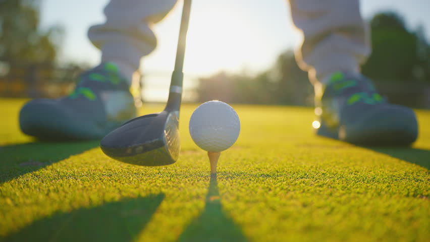 Slow motion golf sport concept, golfer hitting golf ball to hole for winner in golf course is beautiful fairway on sunset. Close up shot tee off on green grass for player playing in summer for relax