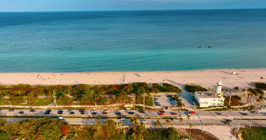 Cars move slowly by the highway through the picturesque beach. Beautiful Miami with the Atlantic Ocean at backdrop.