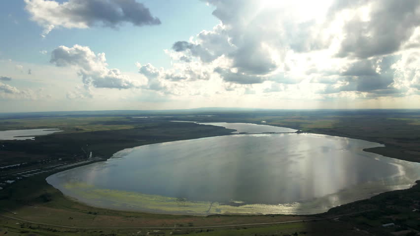Beautiful nature footage of a lake in plain countryside under lush white clouds