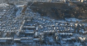 Dramatic aerial footage showcasing a winter wonderland. The video begins with a breathtaking sunrise over a snow-covered city, transitions through snow covered park scenes with frosted trees.