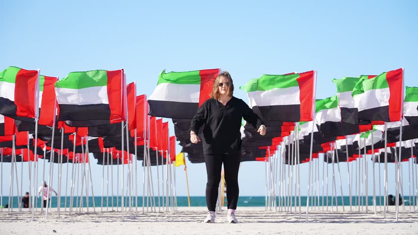 young girl against the backdrop of the sea and UAE flags Royalty-Free Stock Footage #3417907731