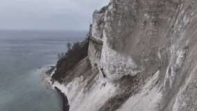 Aerial 4k video of the magnificent chalk cliffs of Møns Klint, rising high above the Baltic Sea. Denmark's highest cliff suspended over the turquoise waters of the Baltic Sea in full view landscape. 