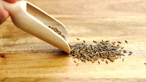 Video shot of spilling cumin seeds out of wooden spoon