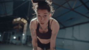 Young tired sportswoman with sweat on her face breathing heavily and looking at camera after intense workout in a gym. Zoom shot, video portrait