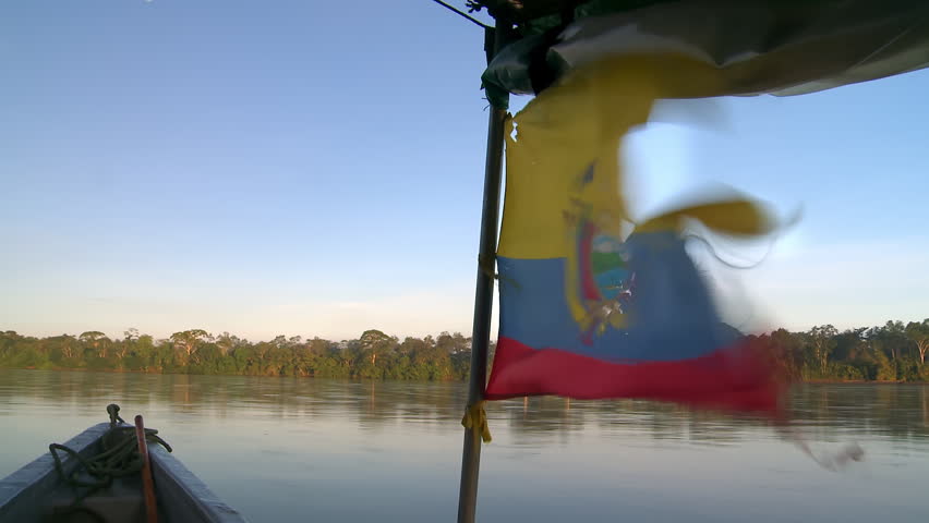 A boat floats down the Rio Napo, Ecuador, in the town of Puerto Francisco de Orellana, also known as El Coca, in South America. Torn Ecuadorian flag on motorboat. Royalty-Free Stock Footage #3418014815