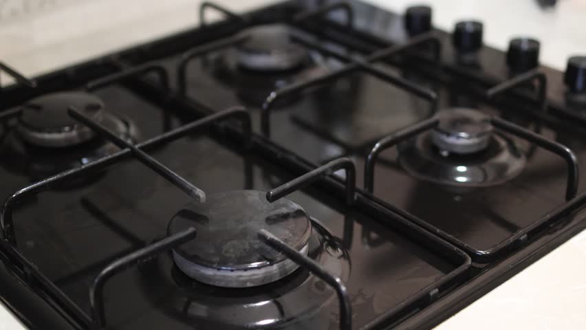woman lights a fire on an automatic electric ignition on an advanced gas stove and puts on it a metal pan