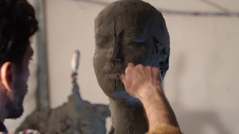 sculptor working female bust from pottery clay