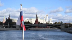 Russian national flag swaying on flagpole of sailing tourboat in a cloudy autumn day in Moscow, Russia. Moscow Kremlin in the background. Soft focus. Real time video.