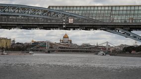 Tourboat sails on Moskva river in a cloudy autumn day in Moscow, Russia. Cathedral of Christ the Saviour in visible under the bridge in the background. Soft focus. Real time handheld video.