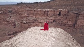 A woman in red is dancing on the cliff of the canyon.