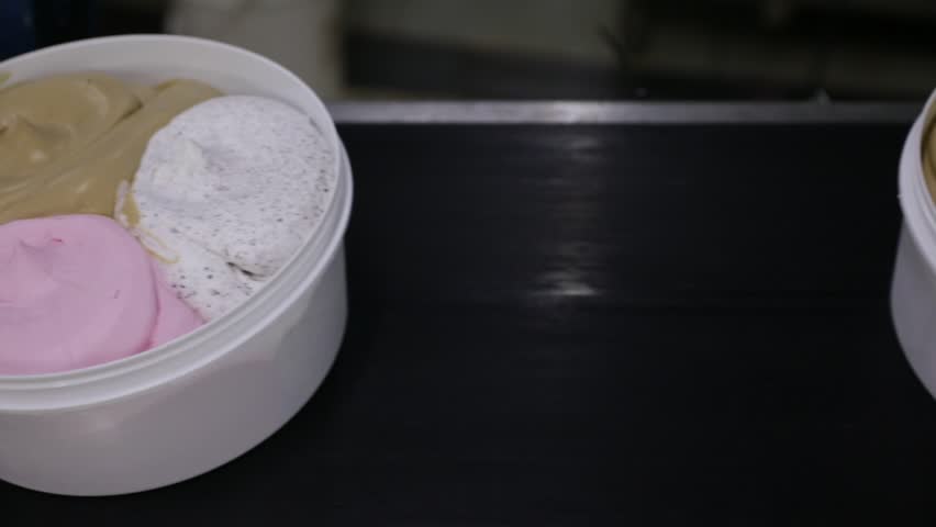 Ice cream factory. Top view of a conveyor belt transporting commercial ice cream pots with different flavors.