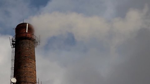 Chimney with smoke on gray sky background