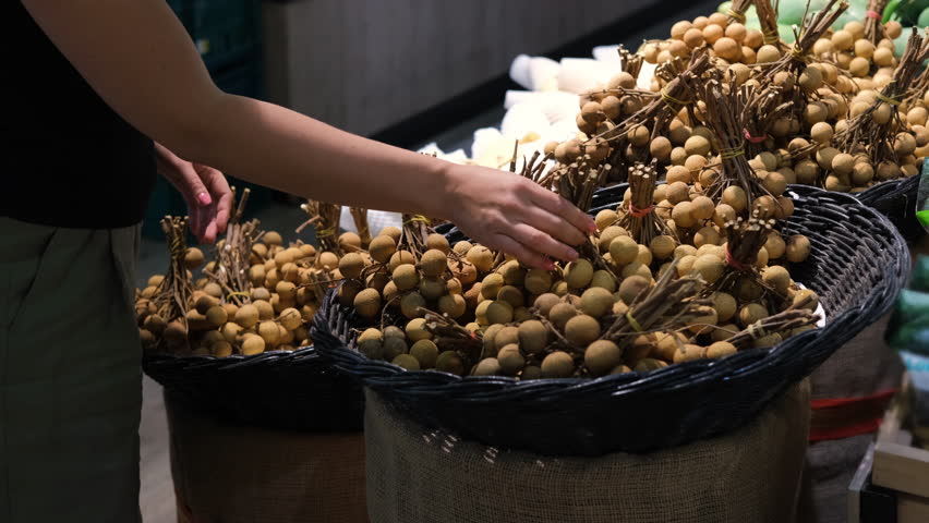 Young woman choosing lychee at grocery store in Thailand, buying exotic tropical fruits. Healthy food concept