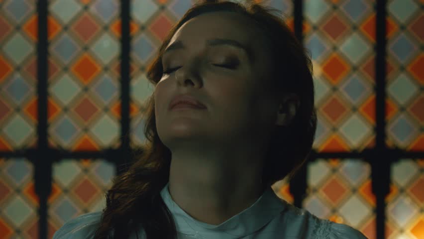 Portrait of a young girl against the background of a colorful stained glass window in a Gothic church. Woman Church Stained Glass Sunlight Alone Cathedral Interior. Fashion and Cinematic concept