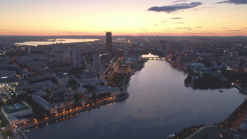 Yekaterinburg at dusk river Iset Metropolis amidst Urals modernity meets history. Metropolis canvas of high-rise buildings and cultural depth From above city