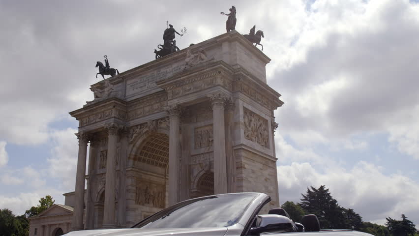 A convertible car under the arch of the peace monument in Milan in Italy