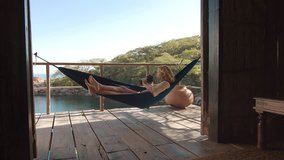 4k Adult woman taking picture with dslr camera on hammock at bungalow / hot of exotic holiday resort.