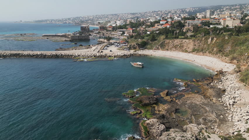 Aerial capture of rocky Mediterranean sea shore in the town of Byblos, Lebanon. Drone video.