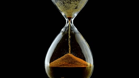 Sand running through hourglass timer with black background. Close up footage of sand time on black background. sand pouring inside an antique transparent hourglass. Time is up Concept. Adlı Stok Video