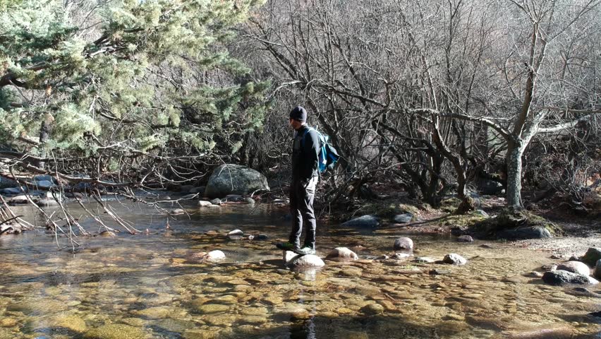 Mountaineer man crossing a river.
