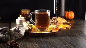 Symbols of autumn and home comfort - pumpkins, hot mulled wine, burning candles, yellow leaves and a warm knitted scarf. Suitable for content about autumn and home comfort.