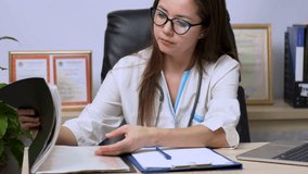 Young female doctor going through paperwork in an office. 4k slow motion