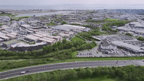 Cars on dual way motor way and Galway city in the background. Warm sunny day. Town traffic. High density urban area mixed with business parks and green zone. Aerial view